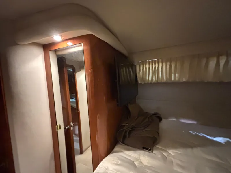 Slide: The Image of 1999 Sea Ray Sundancer 450 cabin interior with bed, seating, and wood accents. - 31