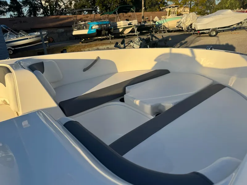 Slide: The Image of 2025 Bayliner Element E16 boat interior with cushioned seating in a marina setting. - 7