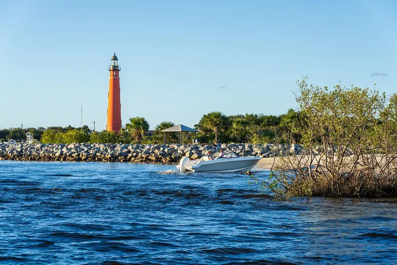 Slide: The Image of 2025 Boston Whaler 210 Vantage near lighthouse and rocky shoreline. - 35