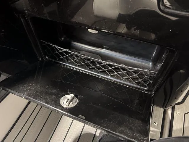 Slide: The Image of Storage compartment of 2025 Yamaha Boats 222SD, featuring a secure latch and netting. - 15