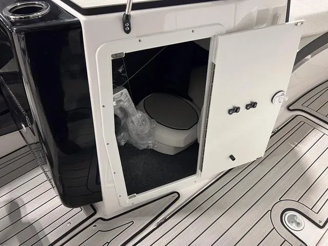 Slide: The Image of 2025 Yamaha Boats 222SD interior storage compartment with toilet, open door view. - 22