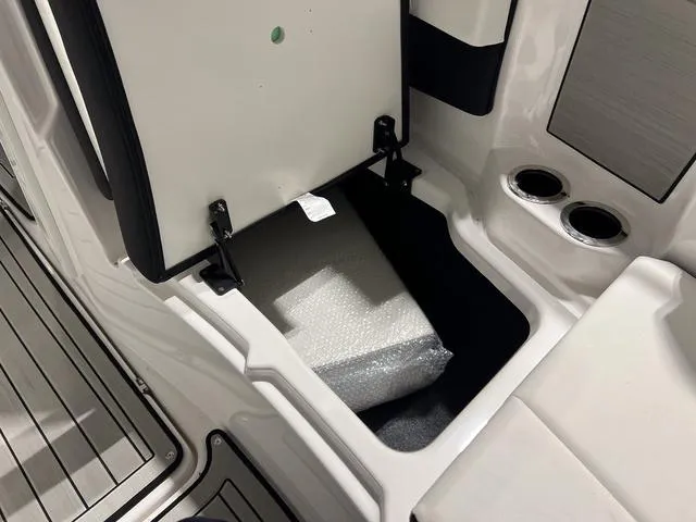 Slide: The Image of 2025 Yamaha Boats 222SD storage compartment with bubble-wrapped item and cup holders. - 27