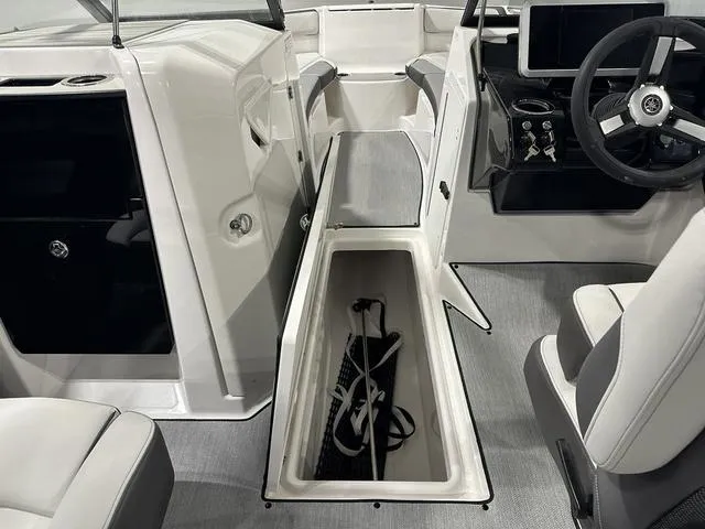 Slide: The Image of 2025 Yamaha Boats AR250 interior with open storage compartment and modern dashboard. - 21