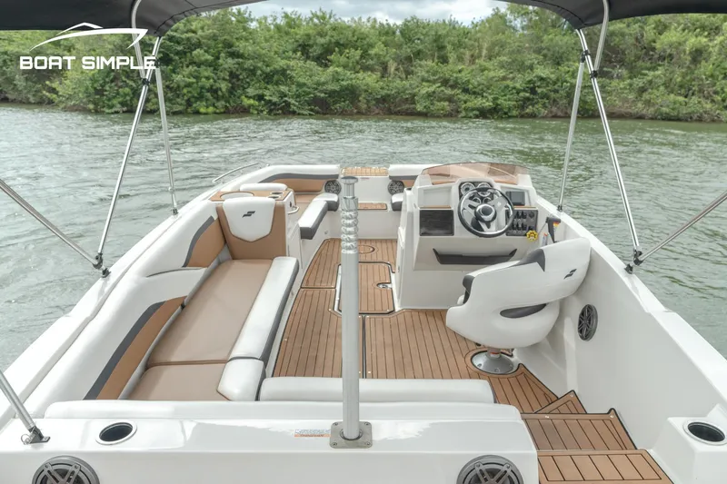 Slide: The Image of 2024 Starcraft SVX 211 OB boat interior with seating and steering wheel on a lake. - 4