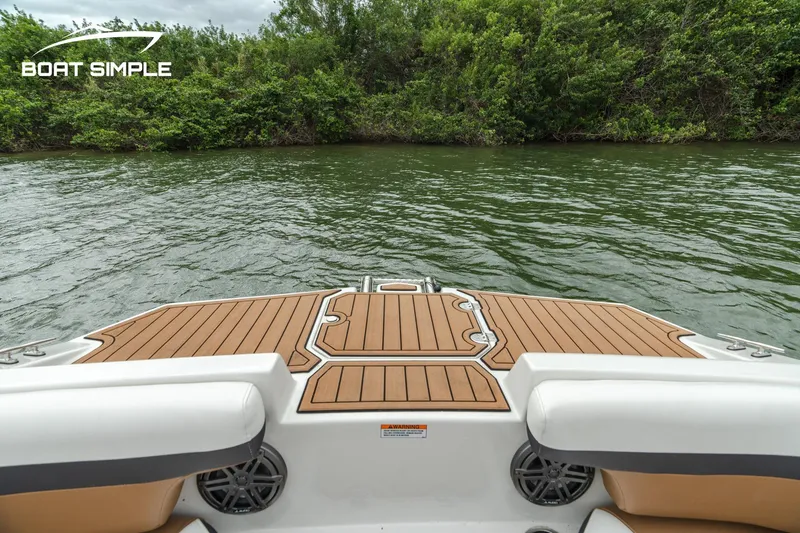 Slide: The Image of 2024 Starcraft SVX 211 OB boat deck with wood finish, overlooking calm water and lush greenery. - 11