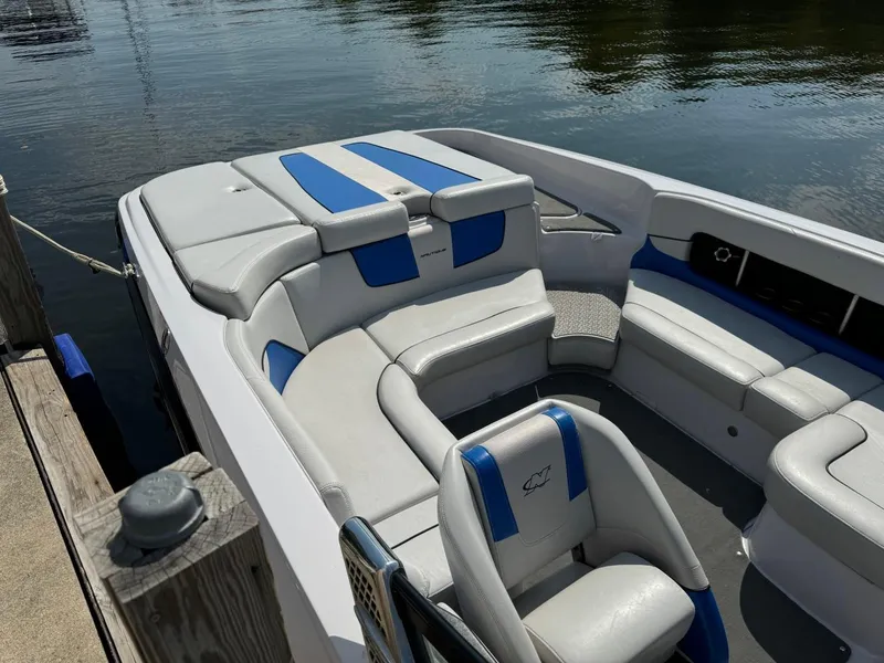 Slide: The Image of 2010 Nautique Sport Nautique 226 boat with white and blue seating, docked by the water. - 3