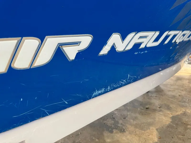 Slide: The Image of Close-up of 2010 Nautique Sport Nautique 226 boat with visible scratches on blue hull. - 32