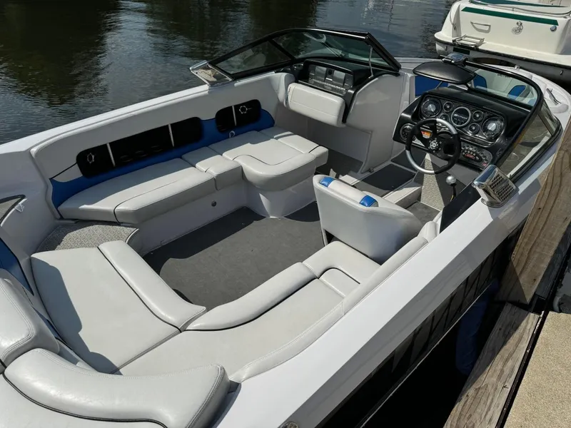 Slide: The Image of 2010 Nautique Sport Nautique 226 boat interior with seating and dashboard, docked by the water. - 4