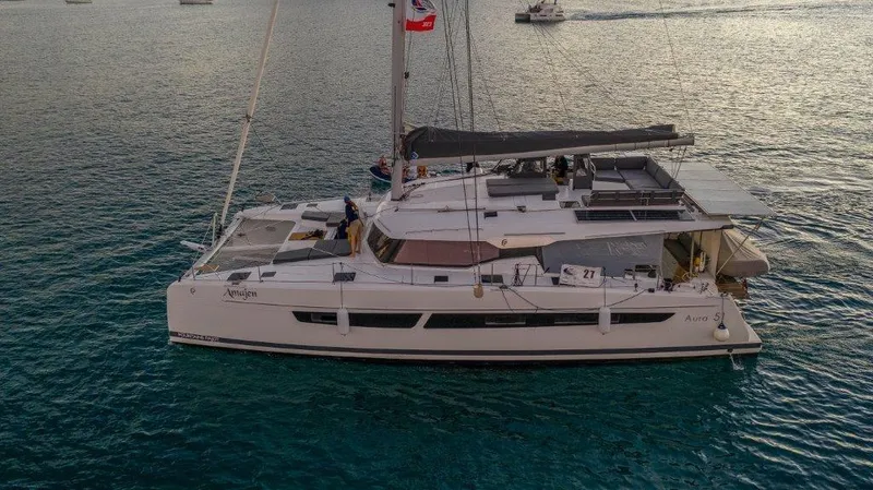 Slide: The Image of 2022 Fountaine Pajot Aura 51 catamaran docked in a marina, surrounded by other boats. - 1