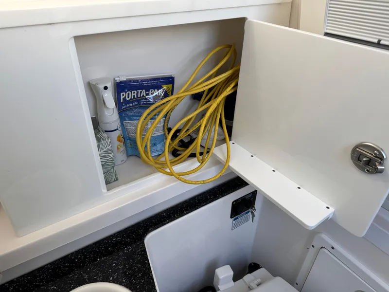 Slide: The Image of Storage compartment in 2022 Sea Fox 328 boat with cleaning supplies and yellow rope. - 28