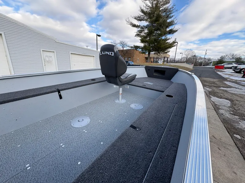 Slide: The Image of 2025 Lund 1600 Fury Tiller boat with seating, docked outdoors under cloudy sky. - 10