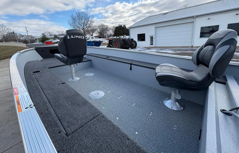 Slide: The Image of 2025 Lund 1600 Fury Tiller boat interior with two seats, parked outdoors. - 11