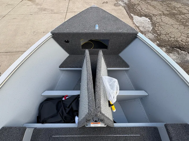 Slide: The Image of 2025 Lund 1600 Fury Tiller boat interior with storage compartments and fishing gear. - 13