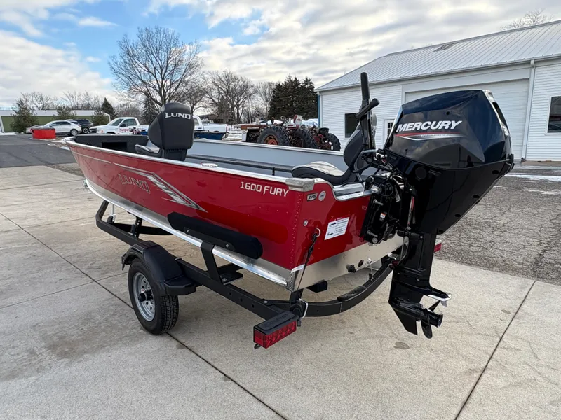 Slide: The Image of 2025 Lund 1600 Fury Tiller boat with Mercury engine on trailer, parked outdoors. - 3