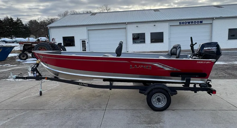 Slide: The Image of 2025 Lund 1600 Fury Tiller boat, red, on trailer, outside showroom. - 4