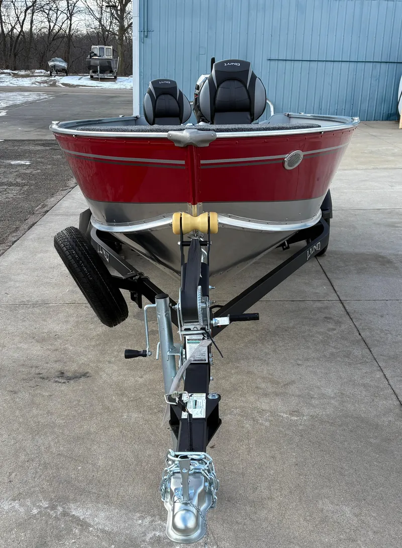 Slide: The Image of 2025 Lund 1600 Fury Tiller boat on trailer, red exterior, parked outdoors. - 6