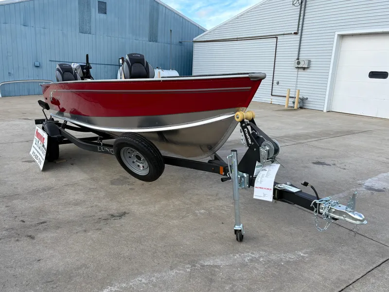 Slide: The Image of 2025 Lund 1600 Fury Tiller boat on trailer, red and silver, parked outdoors. - 7