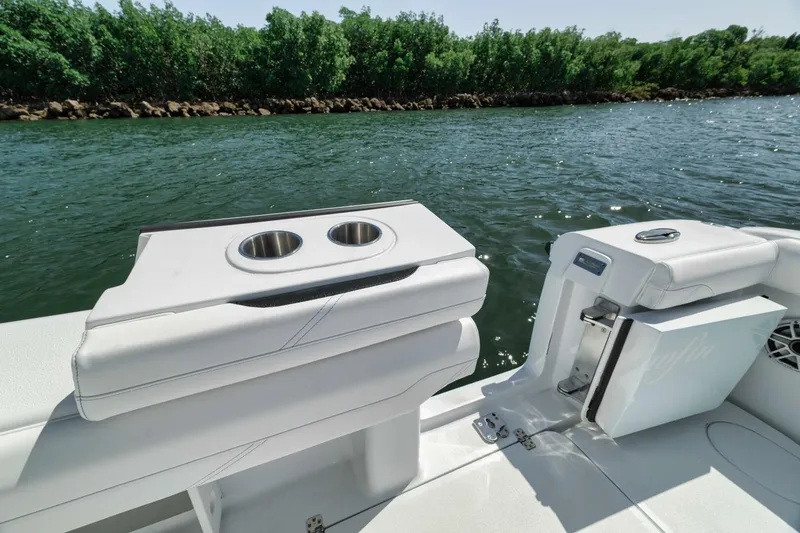 Slide: The Image of 2025 Yellowfin 36 Offshore boat interior with cup holders, near lush shoreline. - 17