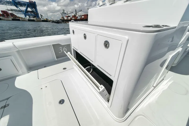 Slide: The Image of 2025 Yellowfin 36 Offshore boat interior with storage compartments, docked near industrial port. - 22