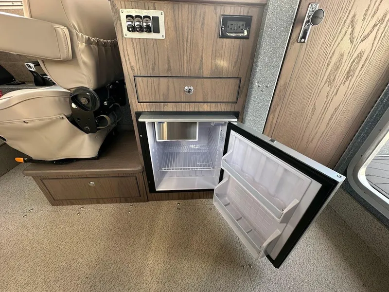 Slide: The Image of 2025 KingFisher 2725 XRS boat interior with open mini fridge and control panel. - 44