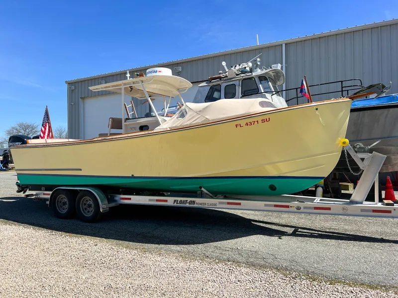 Slide: The Image of 2003 Padebco V27 Center Console boat on trailer, parked outside a warehouse. - 2