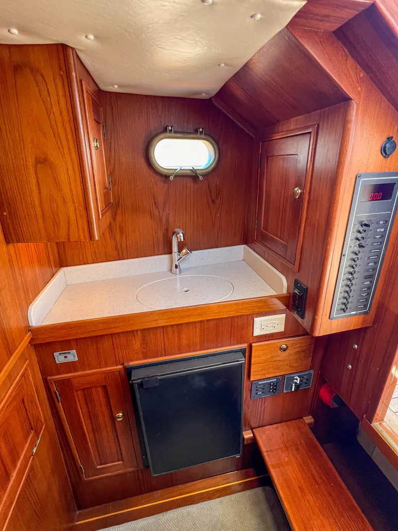 Slide: The Image of 2003 Padebco V27 Center Console cabin interior with wood finish and compact kitchenette. - 22