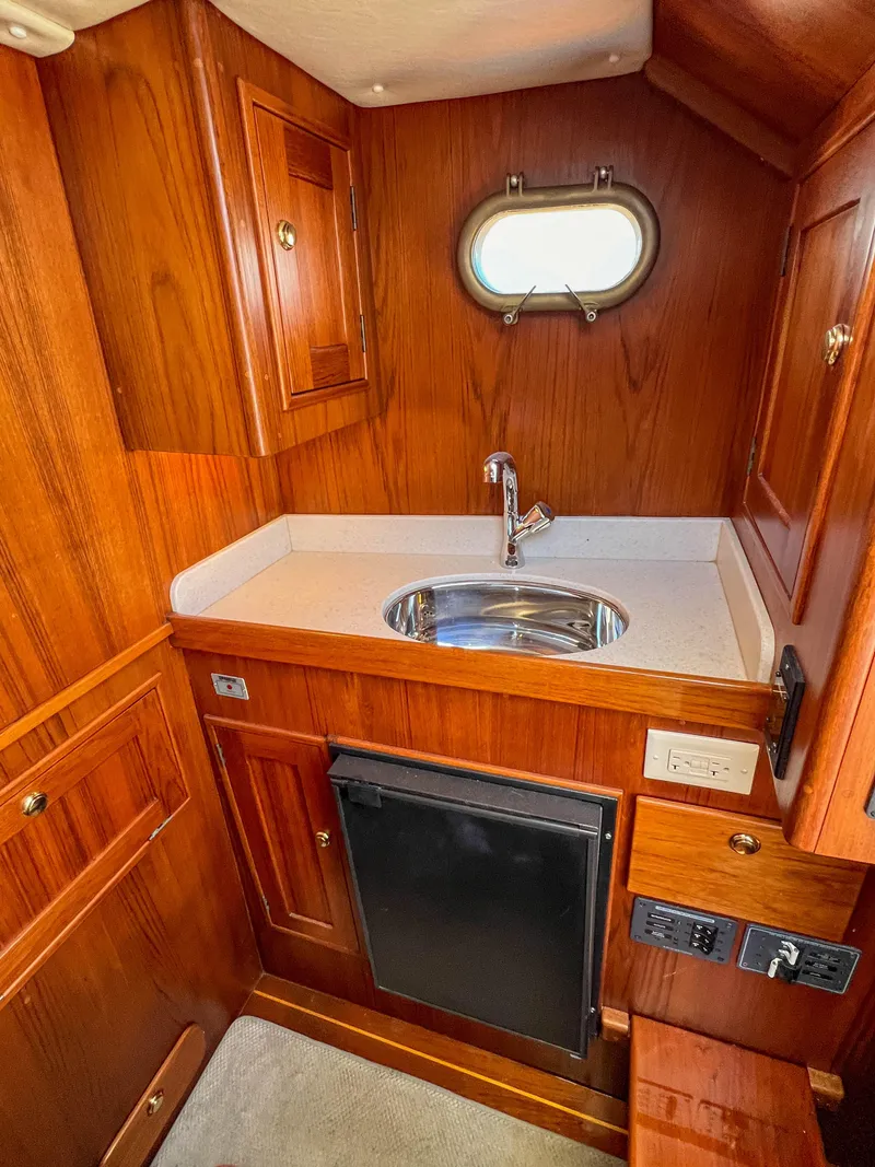 Slide: The Image of 2003 Padebco V27 Center Console cabin with wood finish, sink, and porthole window. - 23