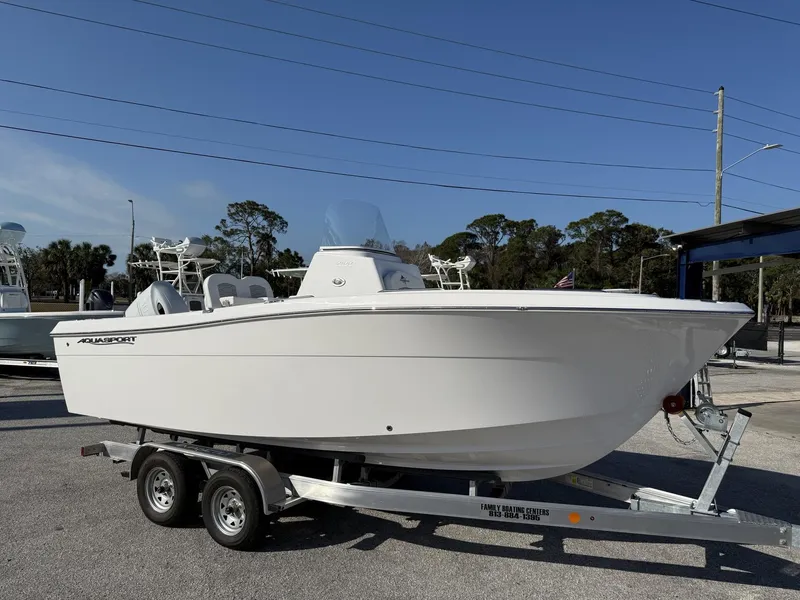Slide: The Image of 2024 Aquasport 2100 CC boat on trailer, parked outdoors under clear sky. - 1