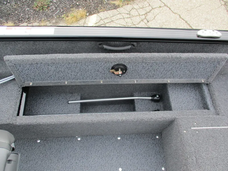 Slide: The Image of 2025 Lund Rebel XL 1650 SS boat storage compartment with carpeted interior and handle. - 8