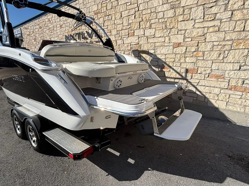 Slide: The Image of 2017 Cobalt R5 boat on trailer, featuring swim platform, parked by stone wall. - 25