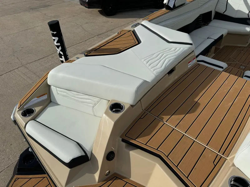 Slide: The Image of 2025 Nautique G23 boat interior with tan and white seating, featuring cup holders and teak flooring. - 11