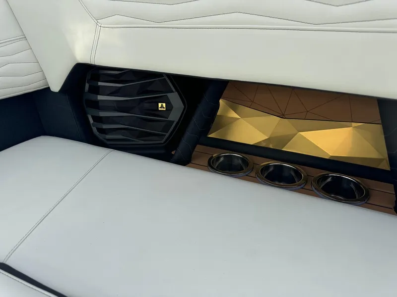 Slide: The Image of 2025 Nautique G23 interior with white seating, speaker, and gold geometric accents. - 22