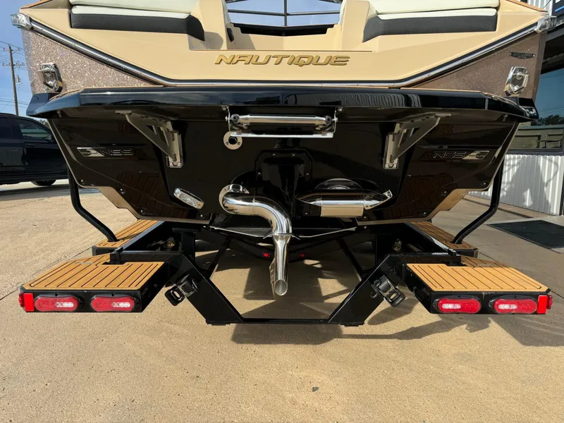 Slide: The Image of 2025 Nautique G23 boat rear view with teak swim platform and exhaust system. - 4