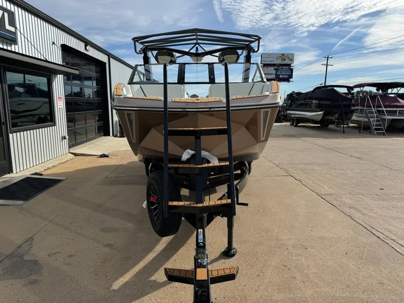 Slide: The Image of 2025 Nautique G23 boat on trailer, parked outside dealership under blue sky. - 8