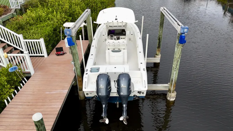 Slide: The Image of 2017 Sea Hunt Gamefish 25 on lift, dual engines, docked by wooden pier. - 3