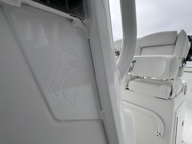 Slide: The Image of 2017 Sea Hunt Gamefish 25 boat interior, featuring clean white seating and dolphin emblem. - 45