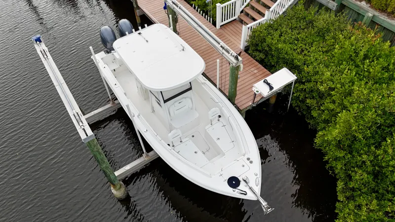 Slide: The Image of 2017 Sea Hunt Gamefish 25 on lift, clean condition, docked by lush greenery. - 5