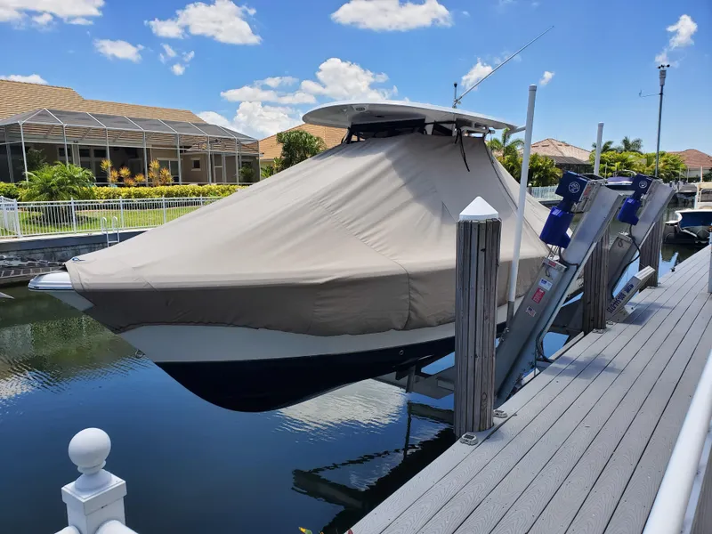Slide: The Image of 2017 Sea Hunt Gamefish 25 on lift, covered, docked by waterfront homes. - 7