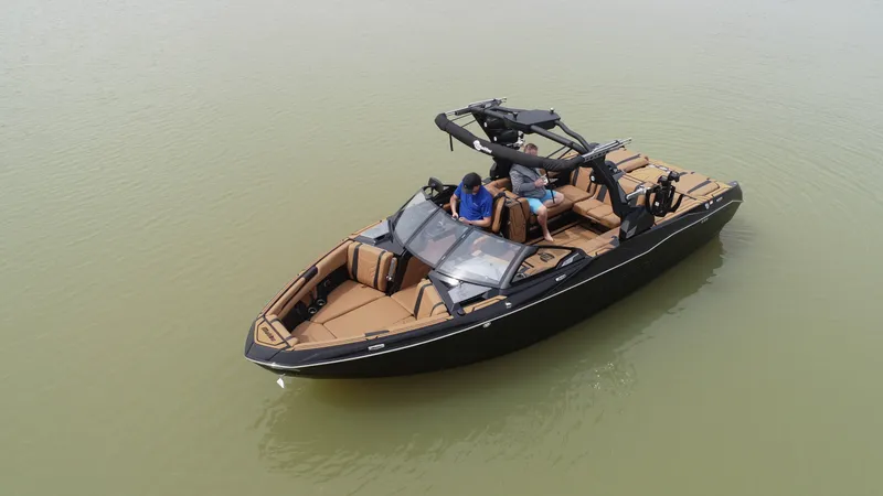 Slide: The Image of 2025 Malibu 25 LSV boat on calm water, featuring sleek design and spacious seating. - 16