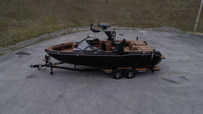 Slide: The Image of 2025 Malibu 25 LSV boat on trailer, black exterior, parked on paved surface. - 19