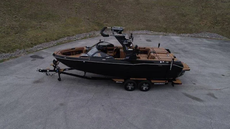 Slide: The Image of 2025 Malibu 25 LSV boat on trailer, parked on asphalt, side view. - 20