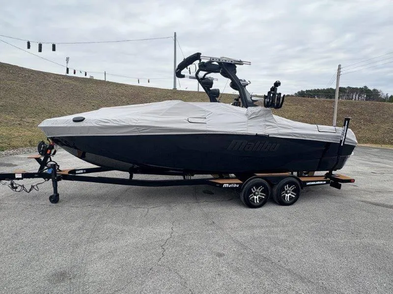 Slide: The Image of 2025 Malibu 25 LSV boat covered on trailer, parked outdoors. - 23