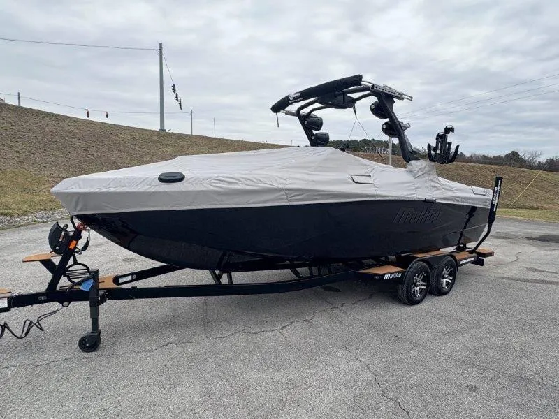 Slide: The Image of 2025 Malibu 25 LSV boat covered on a trailer in a parking lot. - 26