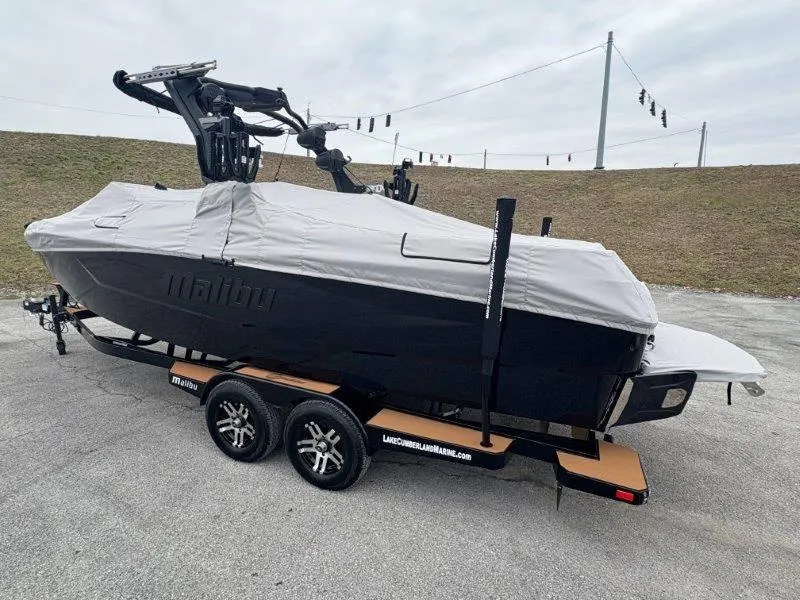 Slide: The Image of 2025 Malibu 25 LSV boat covered on trailer, parked outdoors. - 27