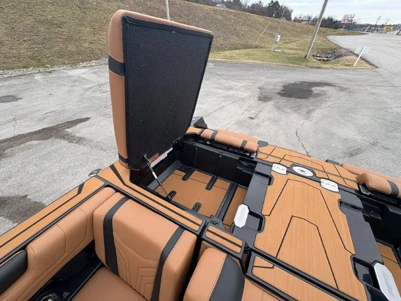 Slide: The Image of 2025 Malibu 25 LSV boat interior with open storage compartment, featuring tan and black seating. - 34