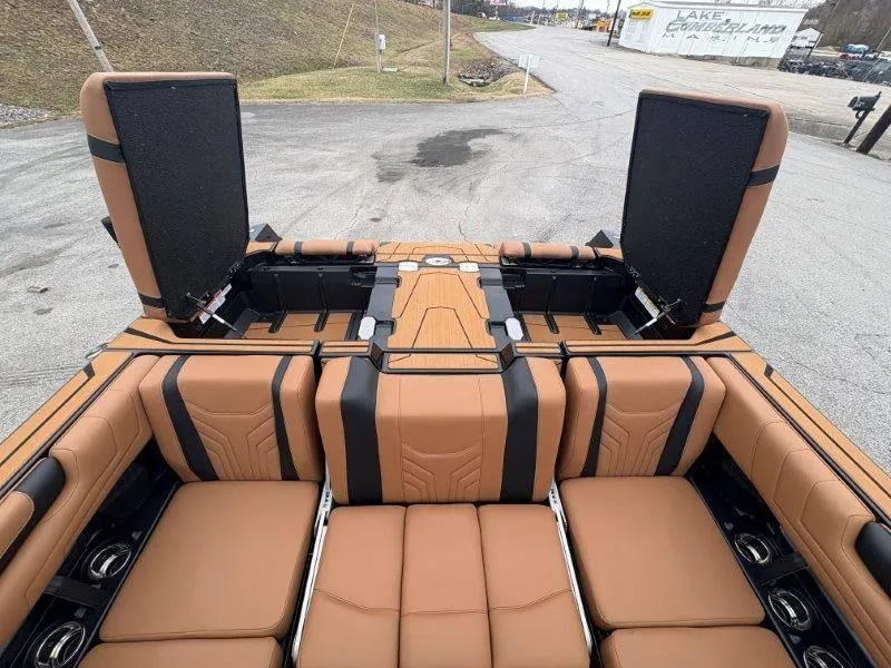 Slide: The Image of 2025 Malibu 25 LSV boat interior with tan and black seating, open storage compartments. - 36
