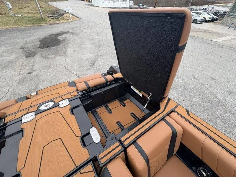 Slide: The Image of 2025 Malibu 25 LSV boat interior with open storage compartment, featuring tan and black seating. - 37