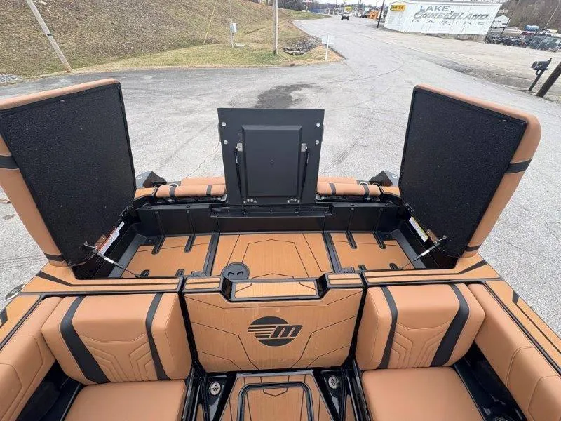 Slide: The Image of 2025 Malibu 25 LSV boat interior with tan seating and open storage compartments. - 38
