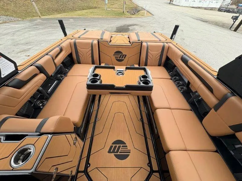 Slide: The Image of 2025 Malibu 25 LSV boat interior with tan seating and central table. - 61