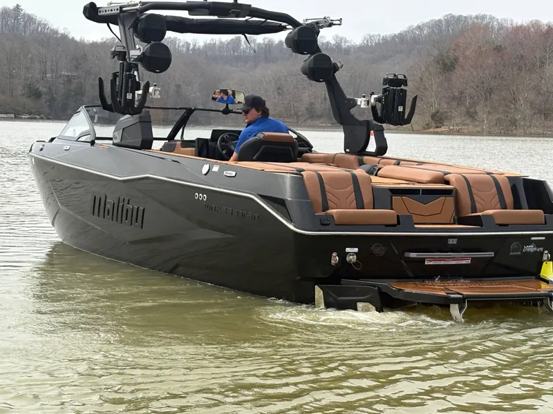 Slide: The Image of 2025 Malibu 25 LSV boat on a lake with a person at the helm. - 8